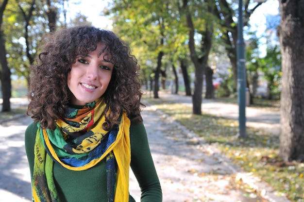 Morena linda mujer joven con bufanda colorida sonriendo al aire libre en la naturaleza