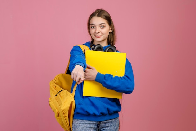 Morena morena em pé segurando mochila amarela e mochila