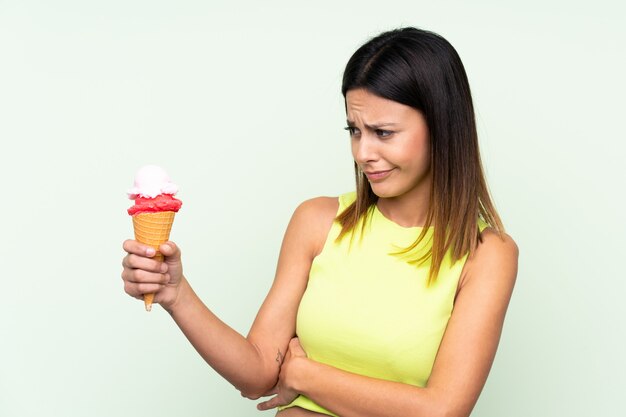 Morena mulher segurando um sorvete de corneta com expressão triste