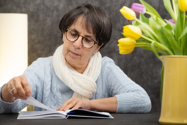 Morena mulher sênior com óculos lendo livro