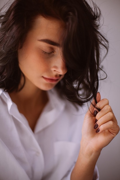 Morena con el pelo rizado con una camisa blanca sentada en el procesamiento de fotos antiguas de la ventana