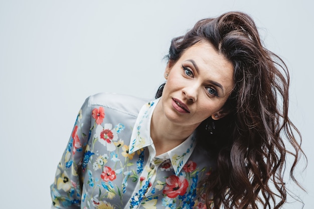 Morena de pelo rizado de primer plano con ojos azules y maquillaje nude en la camisa de color