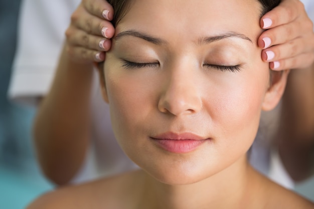 Morena relaxada recebendo uma massagem na cabeça