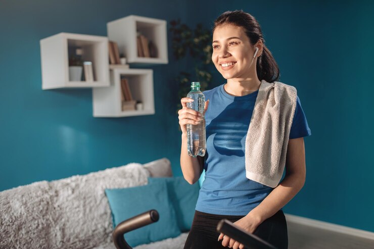 Una morena sonriente bebiendo agua después del entrenamiento