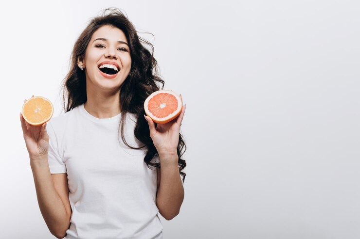 Morena sonriente con mitad de naranja y mitad de pomelo