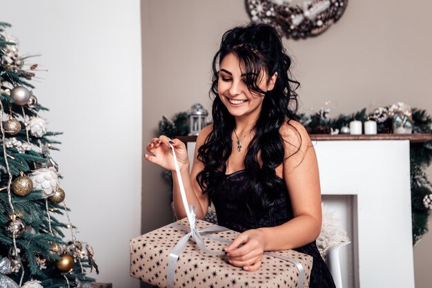 Morena sonriente mujer feliz abriendo caja de regalo de cinta envuelta presente