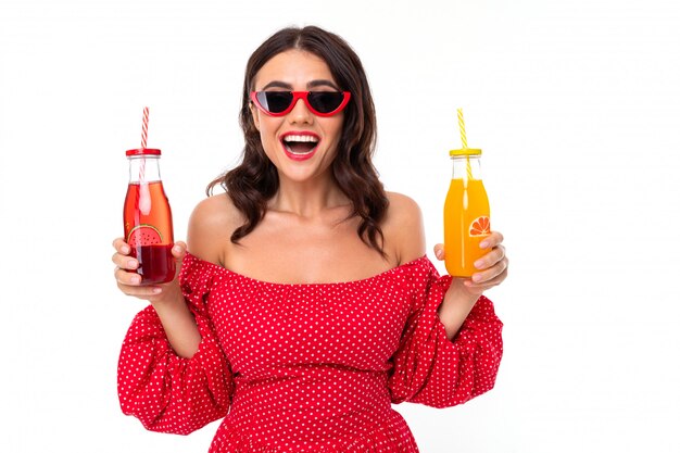 Morena sonriente sosteniendo una bebida, botellas rojas y amarillas