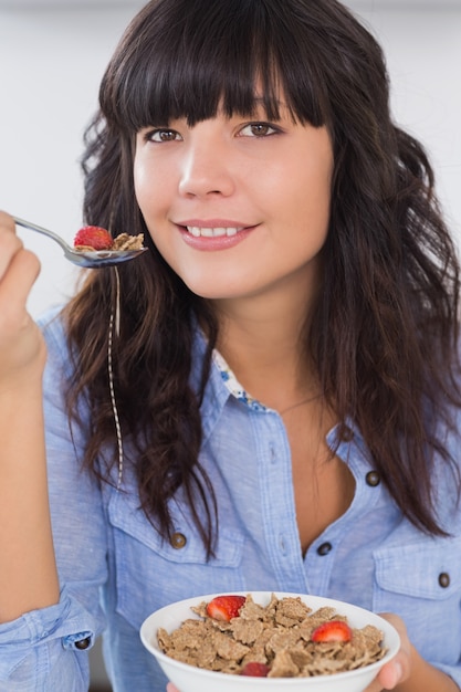 Foto morena sorridente com tigela de cereais e frutas