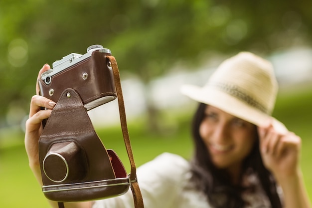 Morena sorridente tomando um selfie com câmera retro