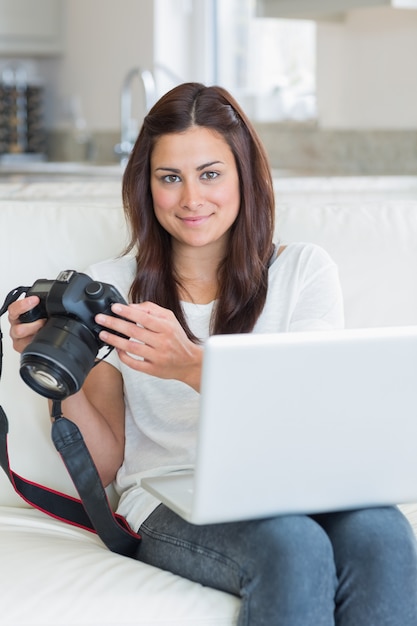 Foto morena sosteniendo una cámara y una computadora portátil