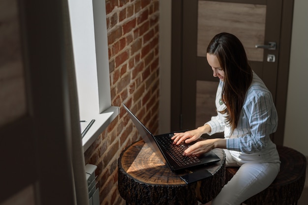 Morena trabaja en una computadora portátil en una habitación en una mesa de madera, independiente