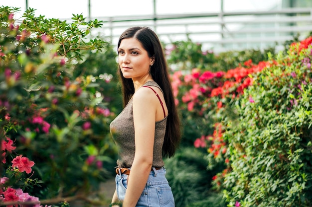 Una morena en vaqueros azules en un paseo por el jardín botánico