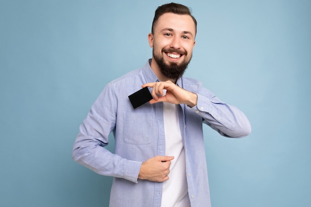 Moreno bonito e sorridente jovem barbudo vestindo uma camisa azul elegante e uma camiseta branca