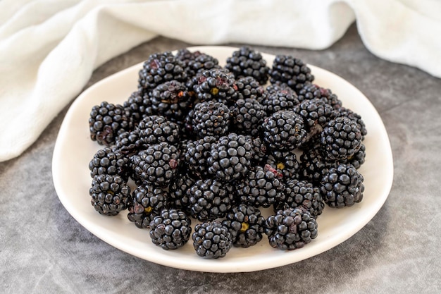 Morera negra sobre fondo oscuro Morera negra fresca y jugosa en el plato Alimentos orgánicos de cerca