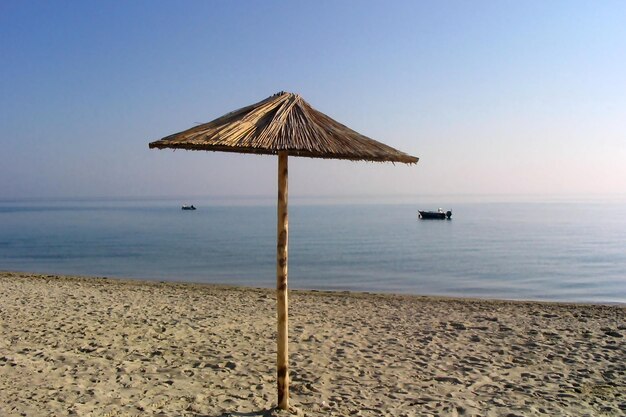 Foto morgen am strand sonnenschirm und zwei boote auf dem meer