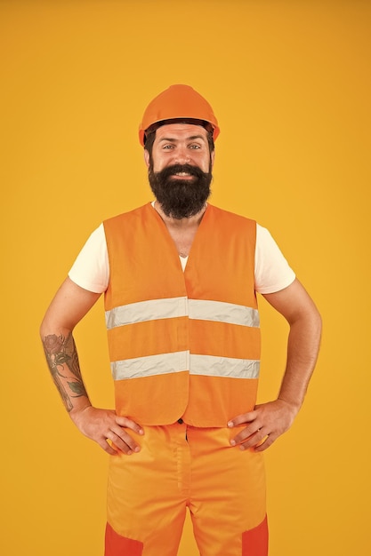 Morgen bauen Bärtiger Mann, der in schützender Arbeitskleidung für die Bautätigkeit lächelt Glücklicher Bausanierungskontructor auf gelbem Hintergrund Bau- und Bauindustrie