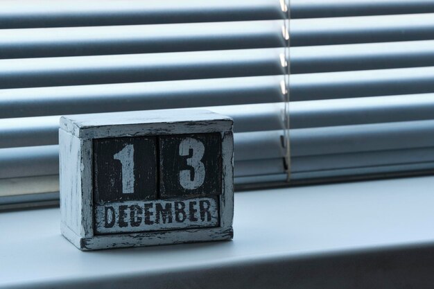 Morgen des 13. Dezember auf einem Holzkalender auf einem Fenster mit Jalousien