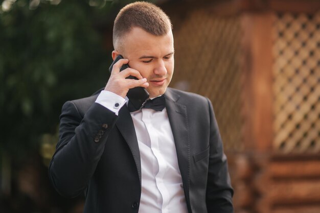 Foto morgen des hübschen bräutigams draußen hochzeitstag hintergrund des grünen baumes sommerzeit