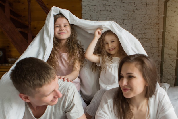 Morgen Familie, die Kinder mit den Eltern, die im Bett spielen und aus einem Traum aufwachen, ich bin gerade aufgewacht, Liebe