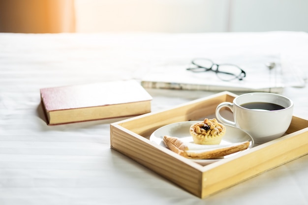 Morgen Kaffee Brot und Buch oder Zeitung auf dem Bett.