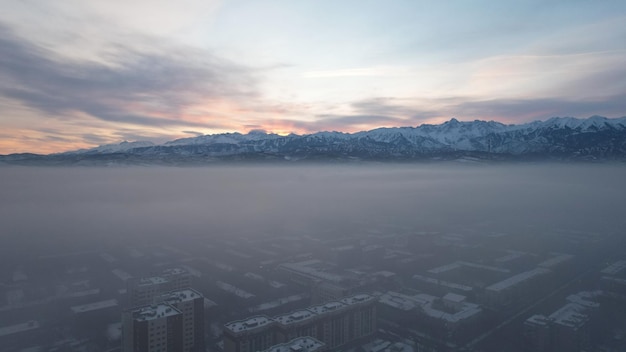 Morgendämmerung über der Stadt im Nebel und Smog mit Blick auf die Berge