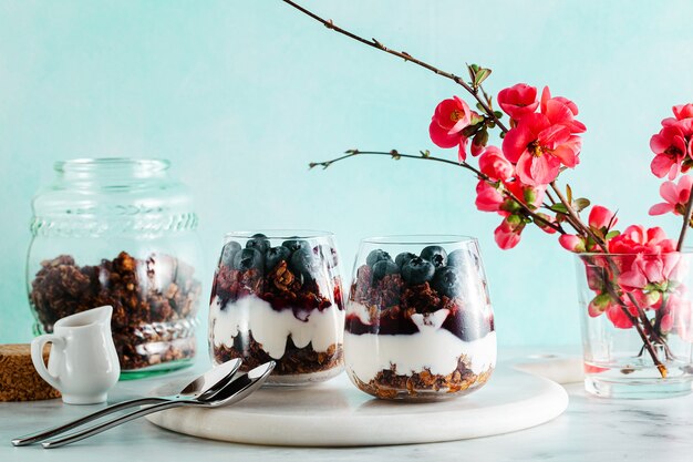 Morgendessert mit Müsli in einem Glas mit Joghurt, Marmelade und frischen Beeren.