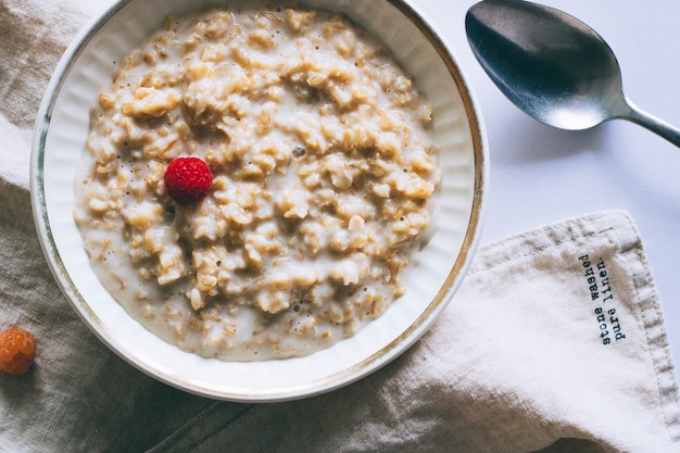 Morgenfrühstück, Hafermehl in der Milch mit Himbeeren auf einem weißen Hintergrund