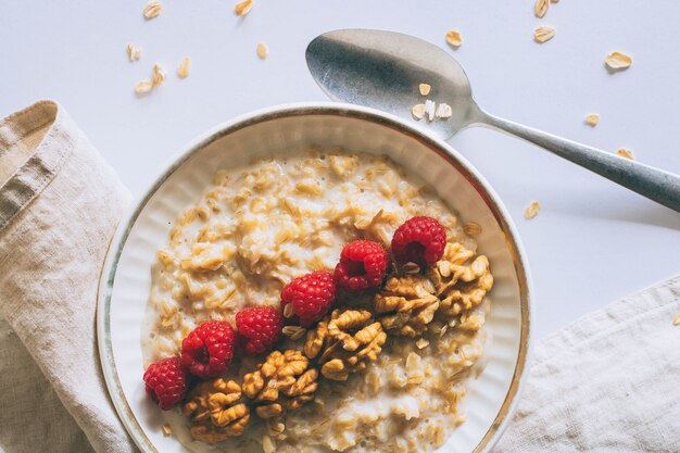 Morgenfrühstück, Hafermehl in der Milch mit Himbeeren auf einem weißen Hintergrund