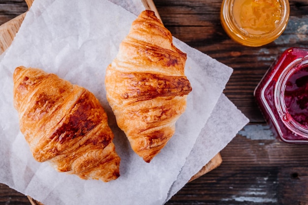 Morgenfrühstück Hausgemachte gebackene Croissants mit Marmelade und Kaffee auf hölzernem rustikalem Hintergrund Draufsicht