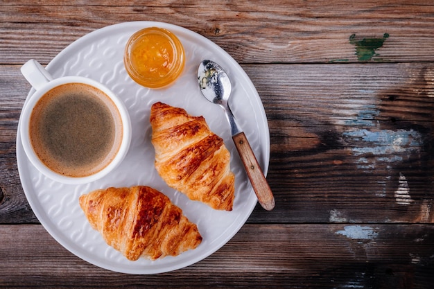 Morgenfrühstück Hausgemachte gebackene Croissants mit Marmelade und Kaffee auf hölzernem rustikalem Hintergrund Draufsicht