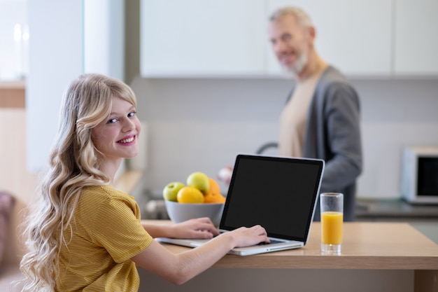 Morgengespräche. Ein blondes Mädchen sitzt in der Küche und redet mit ihrem Vater