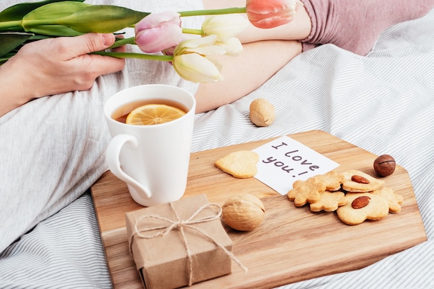 Morgengruß Ihres Lieblingsmädchens. Frühstück, Blumen und ein Geschenk im Bett. Herzlichen Glückwunsch zum Valentinstag am 14. Februar.