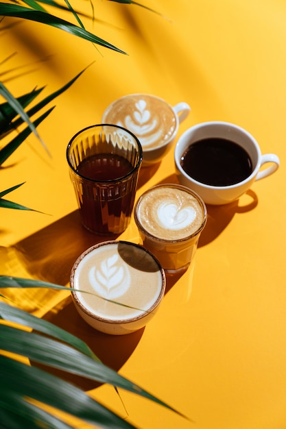 Morgenkaffee auf dem bunten Hintergrund und den Palmenzweigen. Auf unscharfem Hintergrund mit Kopierraum.