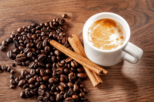 Morgenkaffee Kaffeetasse Zimt und Kaffeebohnen auf Holzhintergrund Draufsicht