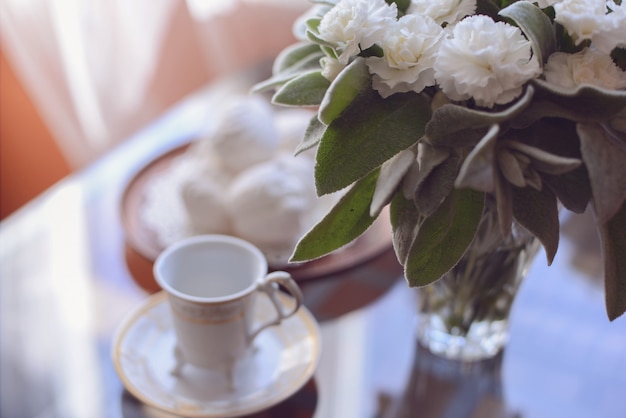 Morgenkaffee mit einem luftigen weißen Eibischnachtisch ein Bündel frische Blumen auf dem Tisch