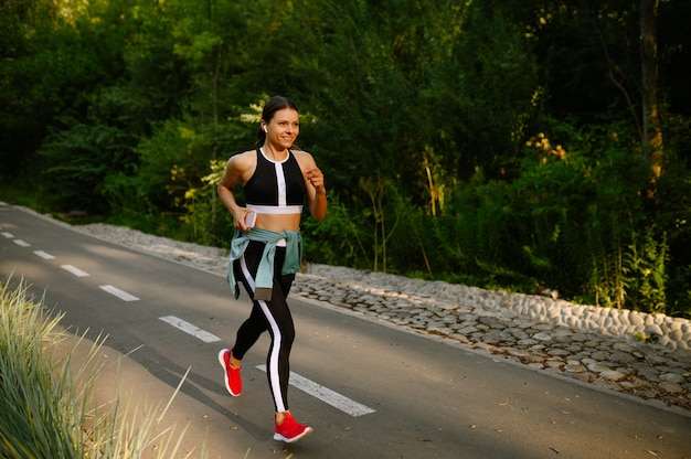 Morgenlauf, Frau beim Training im Sommerpark. Die Läuferin treibt an einem sonnigen Tag Sport