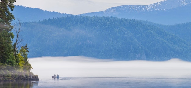 Morgennebel über einem Bergsee Fischer auf dem Boot Teletskoye See Altai