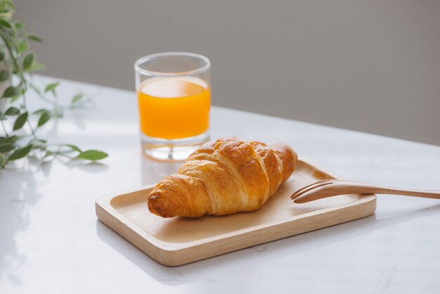 Morgens Frühstück mit Orangensaft und Croissant auf dem Tisch