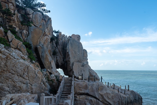 Morgens scheint die Sonne auf die Felsen und Wellen am Strand;