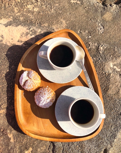 Foto morgens schwarzen kaffee mit eclairs am strand trinken