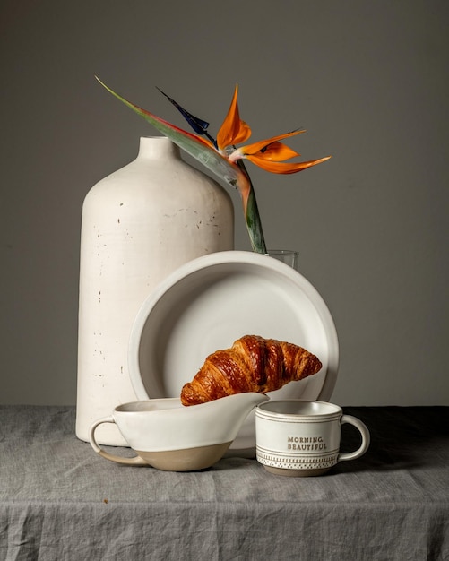 Foto morgenstilllebenschale mit tee, croissant, orangefarbener exotischer blume