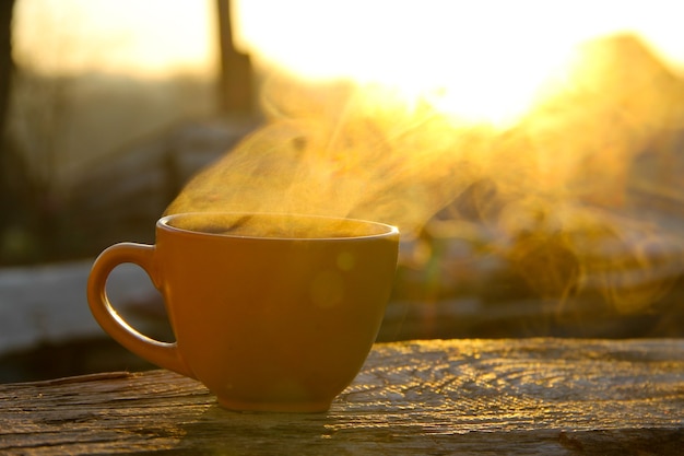 Morgentasse Kaffee auf Holztisch bei Sonnenaufgang