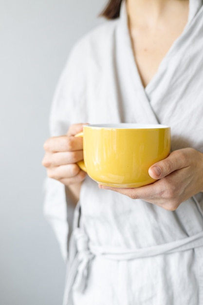 Morgentee mit Zitrone Kaukasische Frau setzt Zitrone in gelbe Tasse des schwarzen Tees