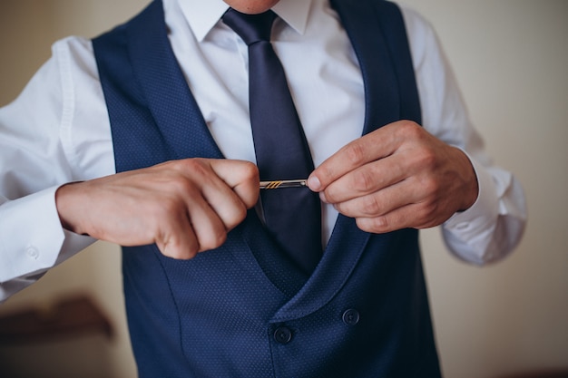 Morgenvorbereitung des Bräutigams, hübscher Bräutigam, der sich anzieht und sich auf die Hochzeit vorbereitet, im dunkelblauen Anzug.