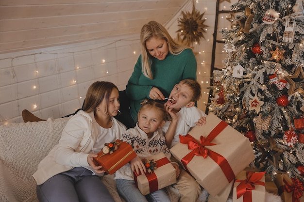 Morher and Kids en el ambiente navideño de año nuevo. La familia está feliz con Navidad y regalos. Niños en el árbol de año nuevo con regalos.