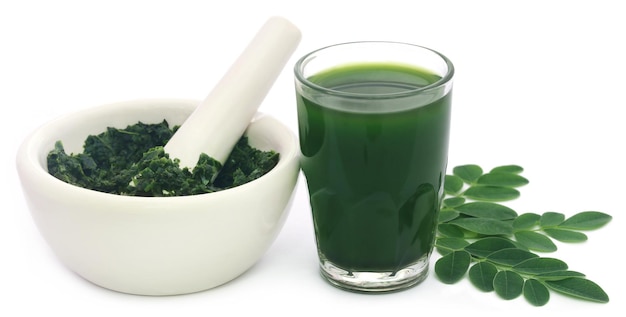 Moringa-Blätter mit Extrakt in einem Glas auf weißem Hintergrund