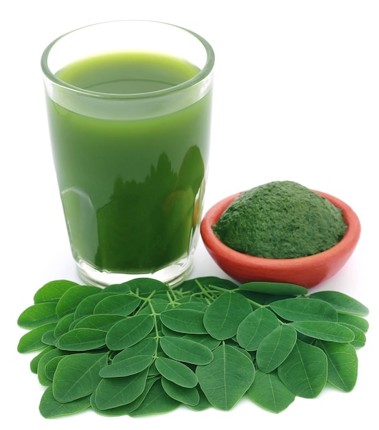 Moringa-Blätter mit Extrakt in einem Glas auf weißem Hintergrund