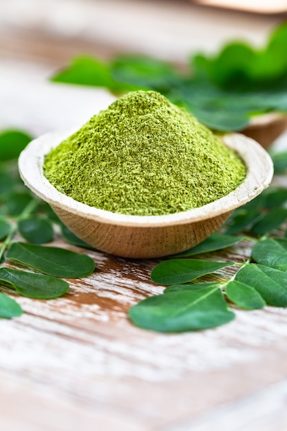 Moringa em pó em tigela de coco com folhas de moringa frescas originais