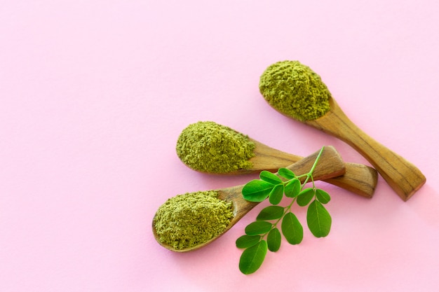 Moringa-Pulver in Holzlöffeln mit originalen frischen Moringa-Blättern