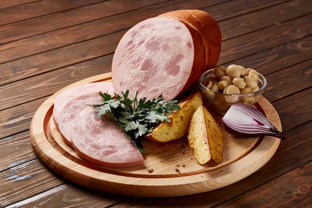 Mortadella mit Gemüse und Kräutern auf einem Holzteller auf einem Holztisch.